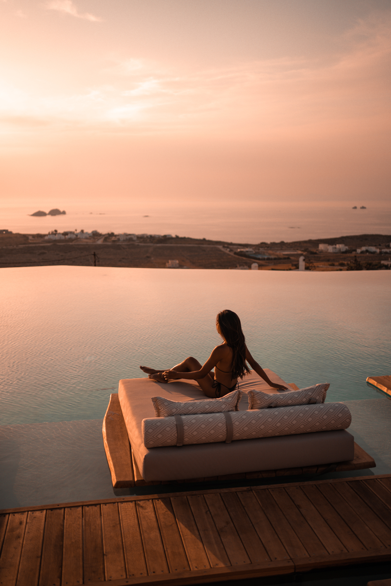 Guest sitting at the edge of the infinity pool during sunset in Paros
