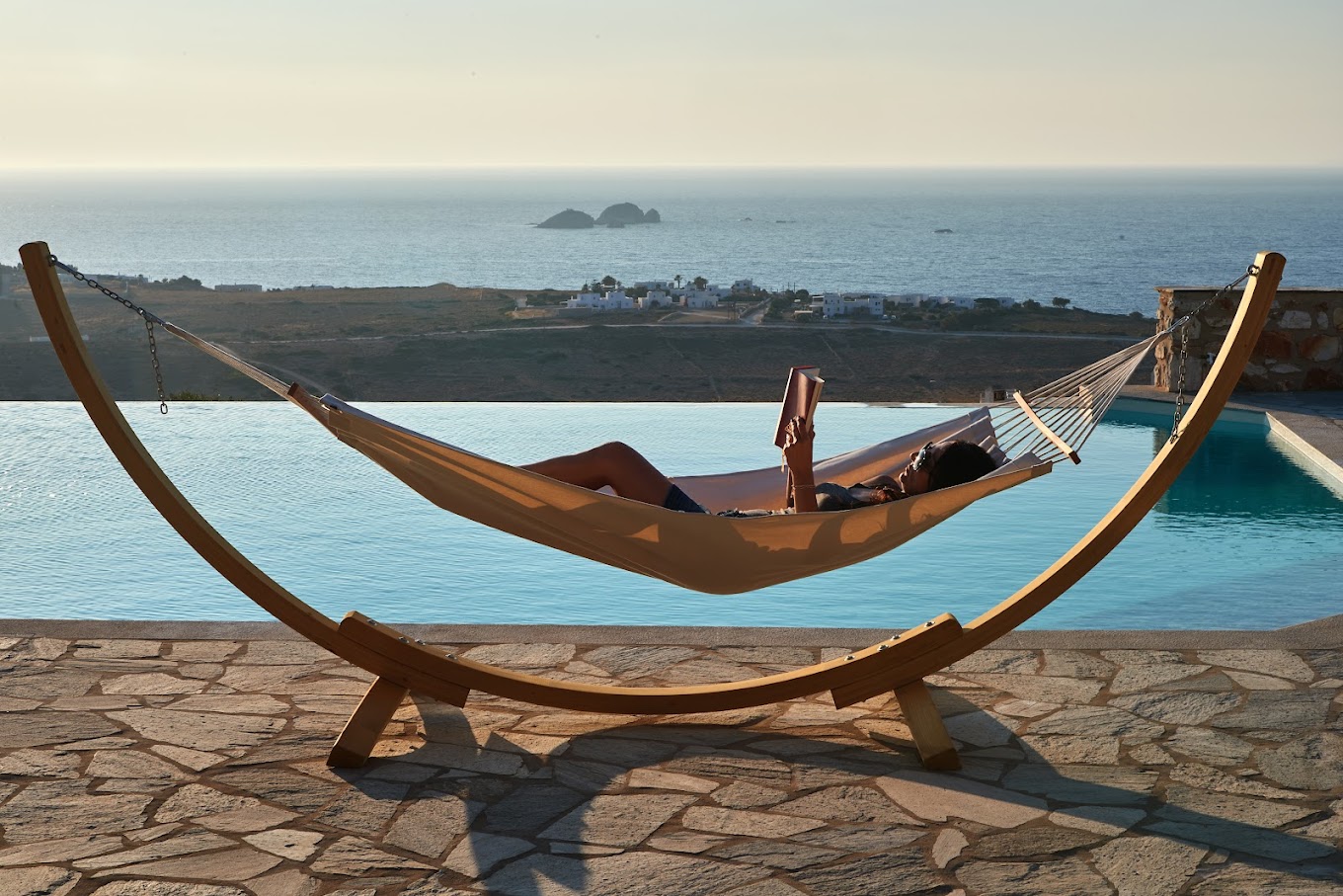 Guest relaxing in a hammock overlooking the sea and pool in Paros
